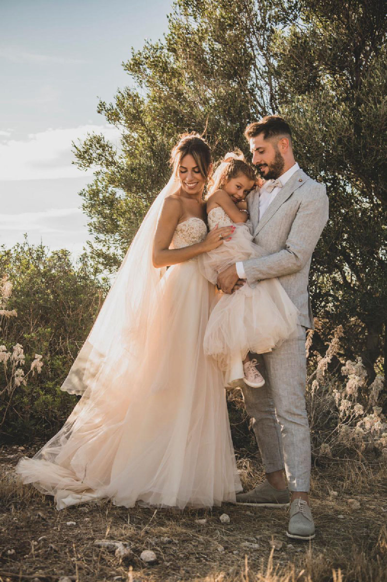 Sposa e sposo con la loro bambina tra gli ulivi